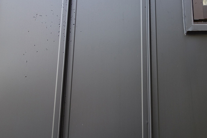 ゼロキューブ（ZERO-CUBE）のガルバリム鋼板の外壁を水で洗い流している様子